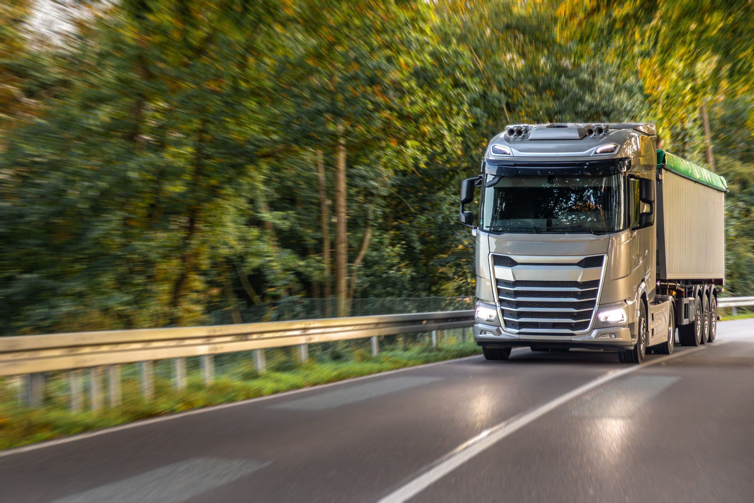 large-modern-truck-winding-road-through-green-forest-freight-logistics